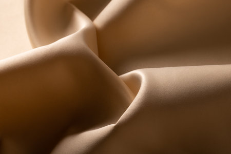 Close up of plain beige satin fabric with folds, copy space. Colour, texture and material.の写真素材