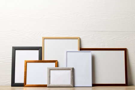 Colourful empty frames with copy space on table against white wall. Mock up frame template, interior...