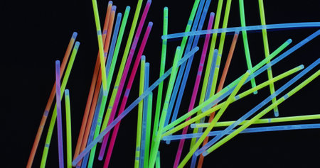 Image of multiple colorful neon glow sticks over black background. Background, copyspace and colours...