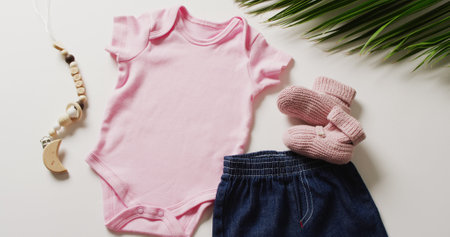 Close up of pink baby gro, booties, denim skirt and toy on white background. Baby clothes and fashion.の写真素材