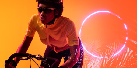 African american female athlete wearing eyewear riding bike by glowing circle and plants, copy space. Composite, sport, cycling, racing, competition, nature, shape and abstract concept.の写真素材