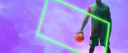Midsection of african american male player with basketball by glowing rectangle on smoky background. Copy space, composite, illuminated, sport, competition, illustration, shape and abstract concept.の写真素材