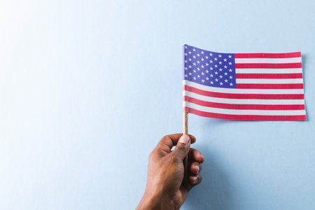 Hand of biracial man holding flag of united states of america with copy space. American patriotism, independence day and tradition concept.の写真素材