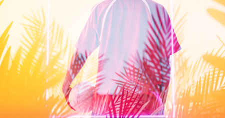 Rear view of biracial female rugby player with ball standing over illuminated rectangle and plants. Copy space, composite, sport, competition, shape, nature, playing, match and abstract concept.の写真素材