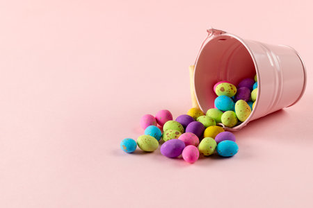 Image of multi coloured easter eggs and pink bucket with copy space on pink background. Easter,...