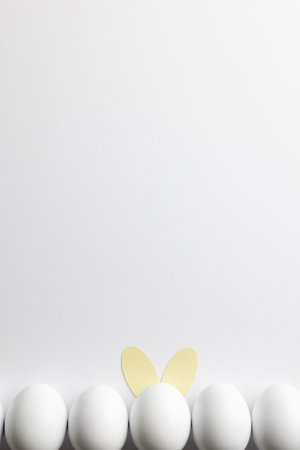 Image of row of white easter eggs with bunny ears and copy space on white background. Easter, religion, tradition and celebration concept.の写真素材