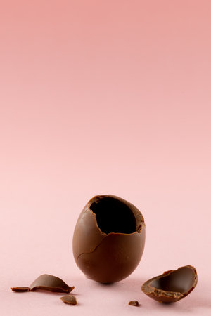 Image of broken chocolate easter egg and copy space on pink background. Easter, religion, tradition...