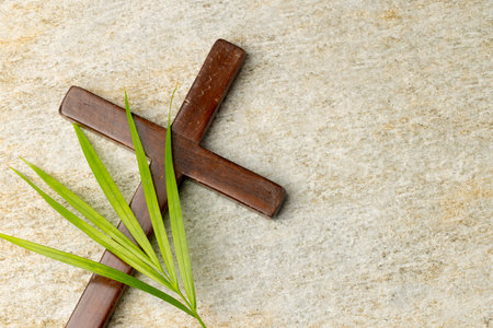 Image of close up of cross with palm leaf and copy space on stone background. Easter, religion, tradition and celebration concept.の写真素材