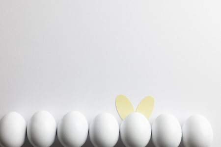 Image of row of white easter eggs with bunny ears and copy space on white background. Easter, religion, tradition and celebration concept.の写真素材