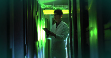 Composition of green light over asian businessman using tablet in server room. Technology, computing...