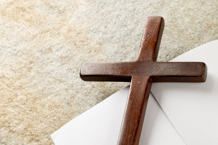 Image of close up of cross with notebook and copy space on stone background. Easter, religion, tradition and celebration concept.の写真素材