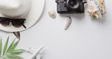 Close up of hat, sunglasses, camera, seashells and plane model on white background with copy space. Travel, vacation and summer.の写真素材
