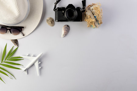 Airplane model, straw hat, sunglasses, camera and seashells on white background with copy space. Travel, transport and vacation.の写真素材