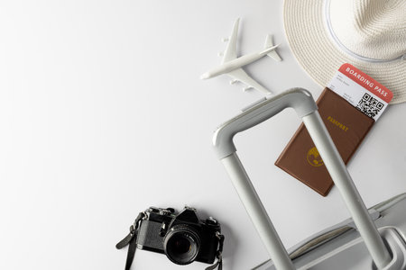Airplane model, straw hat, passport, camera and suitcase on white background with copy space. Travel, transport and vacation.の写真素材