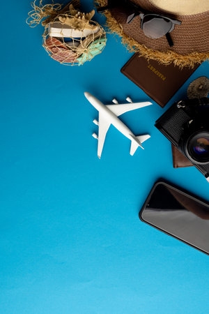 Airplane model, sunglasses, passport, camera and smartphone on blue background with copy space. Travel, transport and vacation.の写真素材