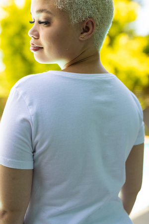 Close up of biracial woman wearing white tshirt over swimming pool in garden. Clothing, material and model.の写真素材