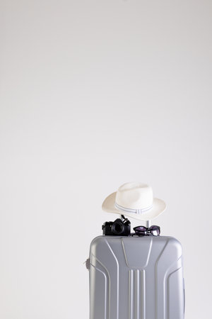 Suitcase with straw hat, sunglasses and camera on white background with copy space. Travel and vacation.の写真素材