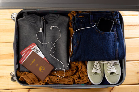 Suitcase with clothes, shoes, passport, tickets, smartphone and earphones on wooden background. Travel and vacation.の写真素材