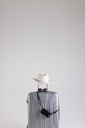 Suitcase with straw hat, sunglasses and camera on white background with copy space. Travel and vacation.の写真素材