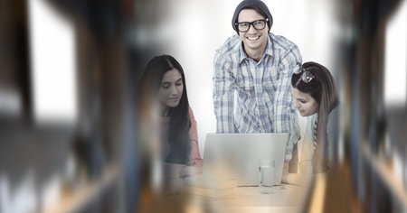 Composition of happy diverse business team using laptop with double exposure. global business and success concept digitally generated image.の写真素材