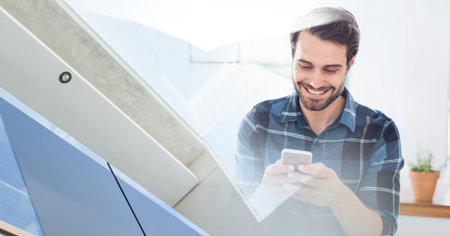 Composition of smiling caucasian businessman using smartphone with modern building. global technology and communication concept digitally generated image.の写真素材