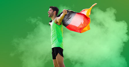 Composition of strong smiling caucasian male athlete holding german flag on green background. sport, fitness and active lifestyle concept digitally generated image.の写真素材