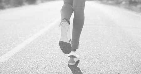 Composition of legs of woman running in street in black and white. sport, fitness and active lifestyle concept digitally generated image.の写真素材