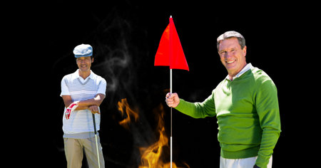 Portrait of diverse senior male golf player smiling against fire flame effect on black background. retirement sports and active senior lifestyle conceptの写真素材