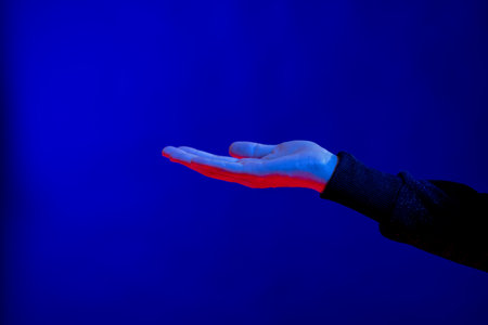 Exposed hand in studio with blue light with copy space. Virtual reality and digital interface...