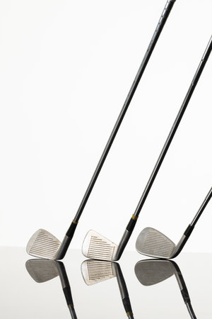 Close up of three golf clubs with copy space and reflection on white background. Golf, sports and competition concept.の写真素材