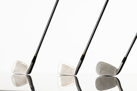 Close up of three golf clubs with copy space and reflection on white background. Golf, sports and competition concept.の写真素材