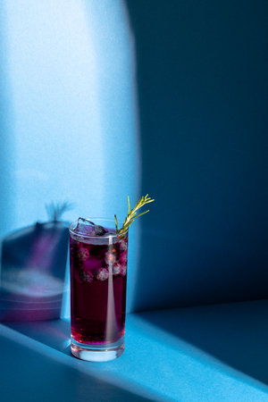 Vertical image of glass with drink and berry on blue background. Drinks, cocktails, beverages and party concept.の写真素材