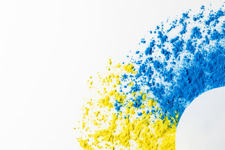 Close up of blue and yellow coloured powder and white circle with copy space on white background. Holi festival, colour, hindu tradition and celebration concept.の写真素材