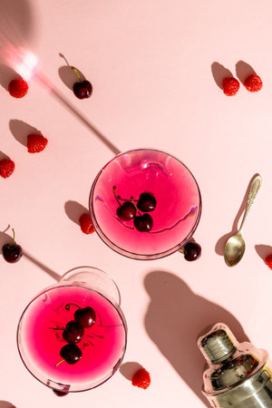 Vertical image of glasses with drinks and fruits over pale pink background with shadows. Drinks, cocktails, beverages and party concept.の写真素材
