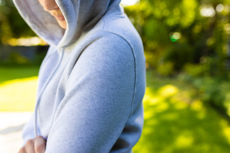 Mid section of caucasian woman wearing gray hoodie over green park on sunny day. Clothing, material and model.の写真素材