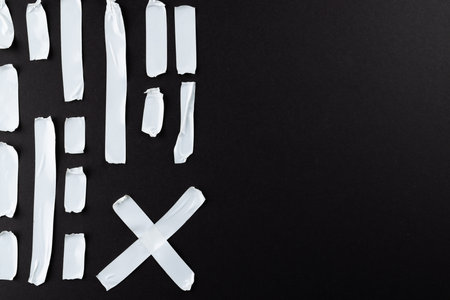 Ripped up pieces of white tape with copy space on black background. Abstract paper texture...