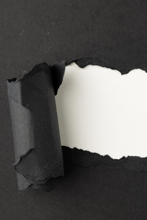 Ripped up piece of black paper with copy space on white background. Abstract paper texture background and communication concept.の写真素材