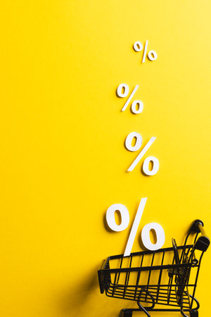 Shopping trolley and white percent signs with copy space on yellow background. Black friday, cyber monday, shopping, cyber shopping, sales, retail and shipping concept.の写真素材