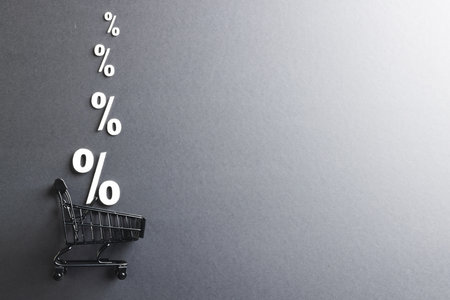 Shopping trolley and white percent signs with copy space on grey background. Black friday, cyber monday, shopping, cyber shopping, sales, retail and shipping concept.の写真素材