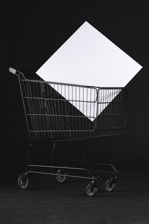 Vertical image of shopping trolley with blank canvas and copy space over black background. Cyber monday, black friday, online shopping, shipping and global connections concept.の写真素材