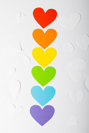 Overhead view of colorful heart shaped arranged in a row on white background, copy space. Rainbow flag, love, lgbtqia rights, freedom, equality and pride concept.の写真素材