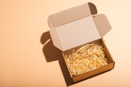 Open box with straw lining and copy space over cream background. Cyber monday, black friday, online...