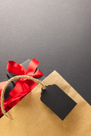 Vertical image of gift boxes with ribbon, gift bag with copy space over black background. Cyber monday, black friday, online shopping, shipping and global connections concept.の写真素材