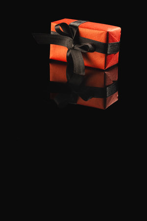 Red gift box with ribbon and copy space over black background. Cyber monday, black friday, online shopping, shipping and global connections concept.の写真素材