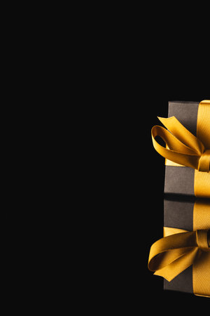 Black gift box with ribbon and copy space over black background. Cyber monday, black friday, online shopping, shipping and global connections concept.の写真素材