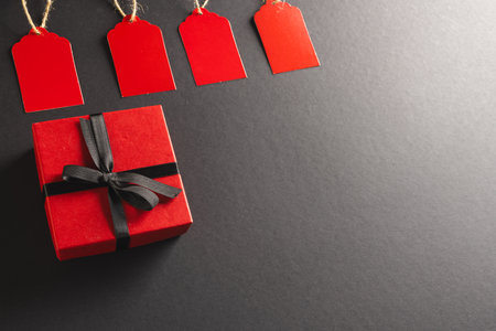 Red gift tags and red gift box with copy space over black background. Cyber monday, black friday, online shopping, shipping and global connections concept.の写真素材