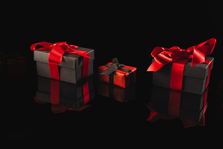 Black and red gift boxes with ribbon and copy space over black background. Cyber monday, black...