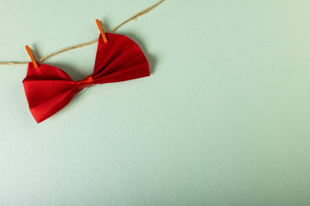 High angle view of red bowtie hanging with clothespins on clothesline on white background. Copy space, menswear, fashion, elegance concept.の写真素材