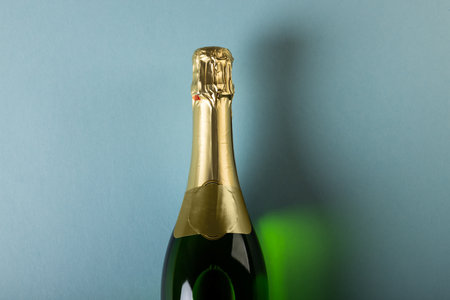 Overhead close-up of champagne bottle isolated over blue background, copy space. Alcohol, drink, liquor and celebration concept.の写真素材