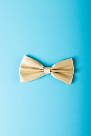 Overhead view of white bowtie isolated against blue background, copy space. Menswear, fashion and...